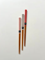 Set of wooden chopsticks with black labels on a light gray background