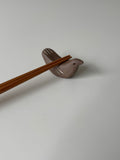Chopstick rest shaped like a bird with wooden chopsticks on a light gray background