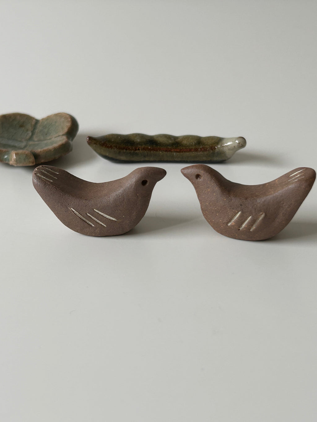 Two ceramic birds chopstick rest on a light gray background