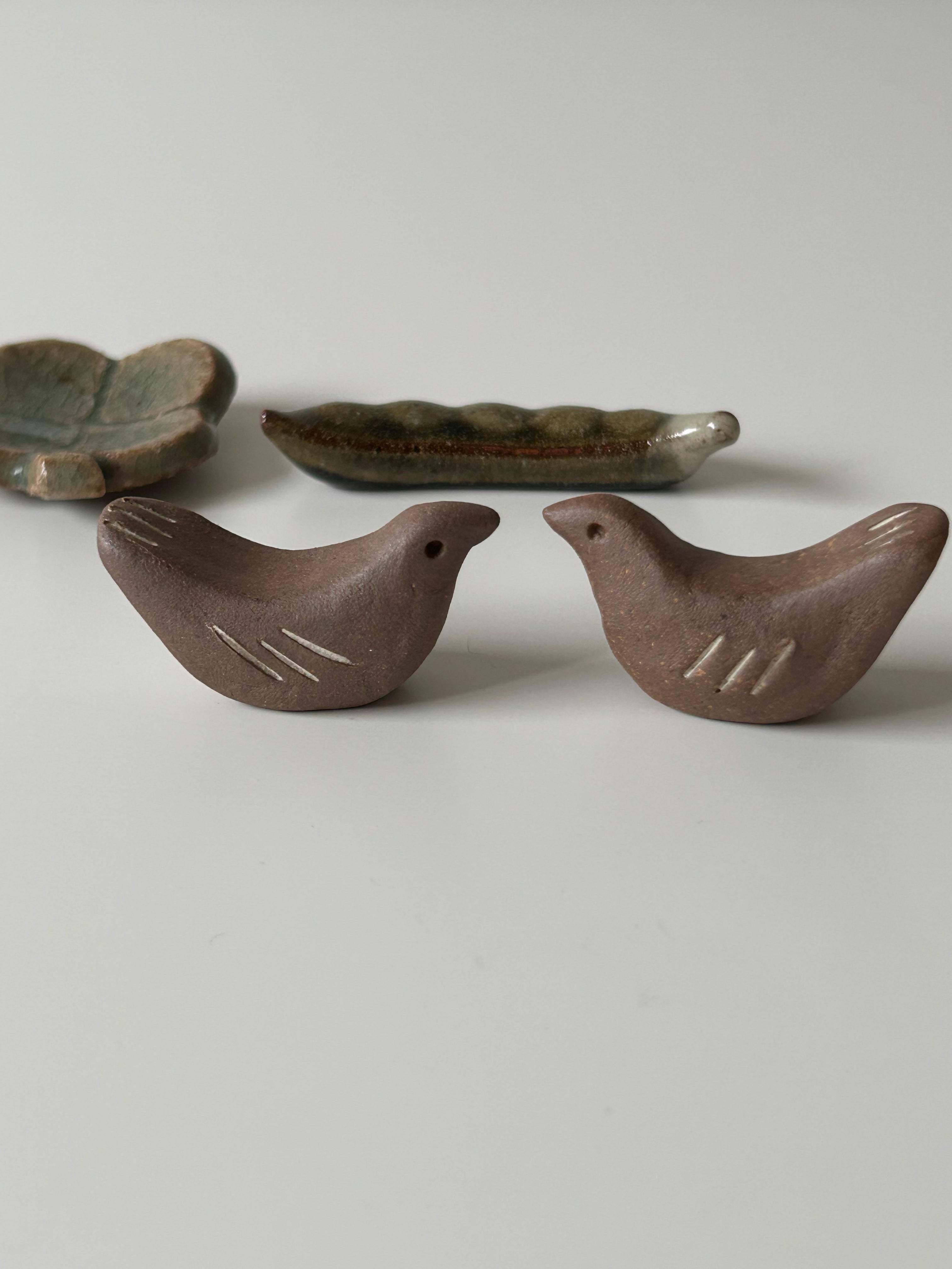 Two ceramic birds chopstick rest on a light gray background