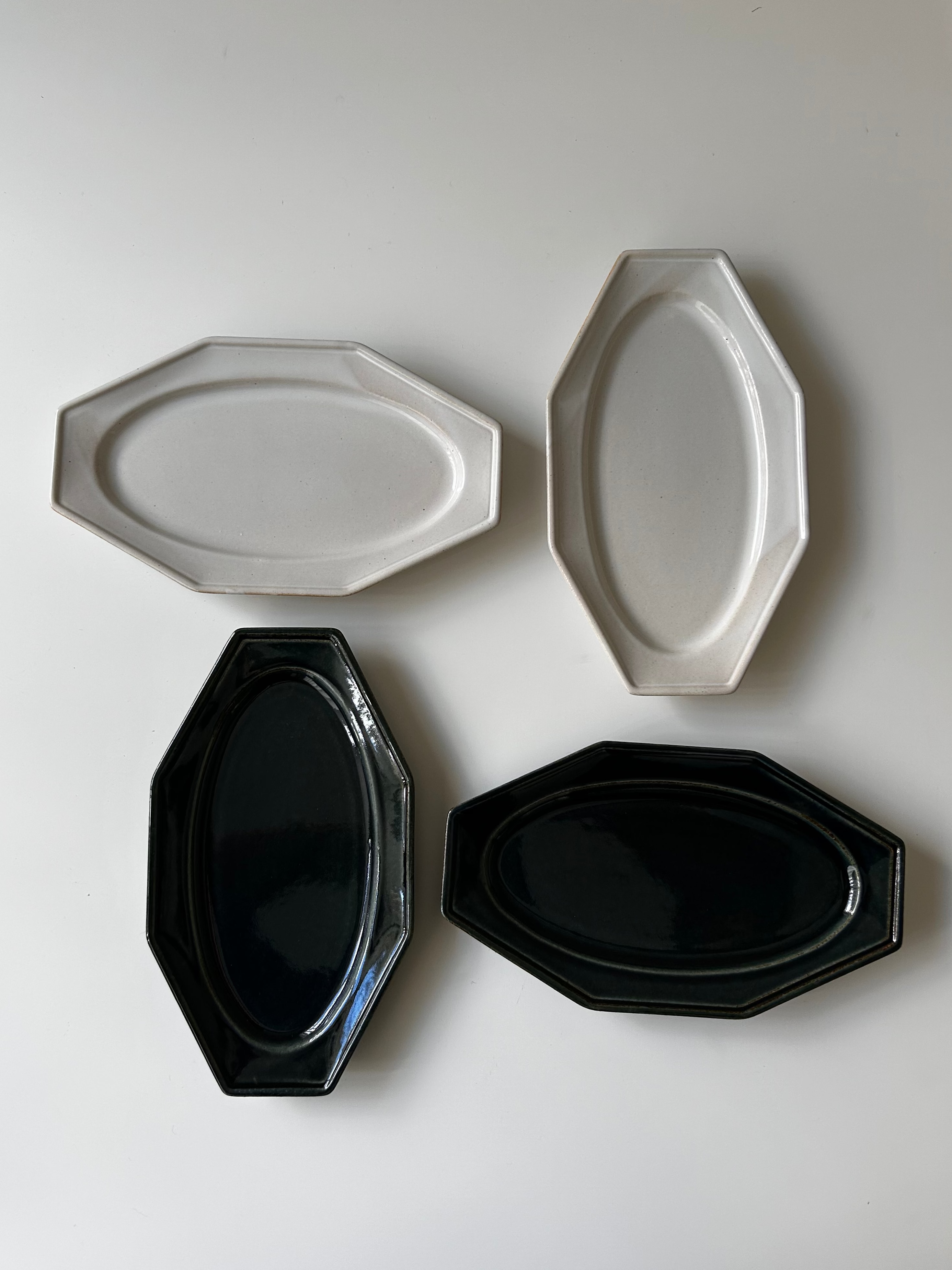 Four oval-shaped plates in black and white on a light gray background