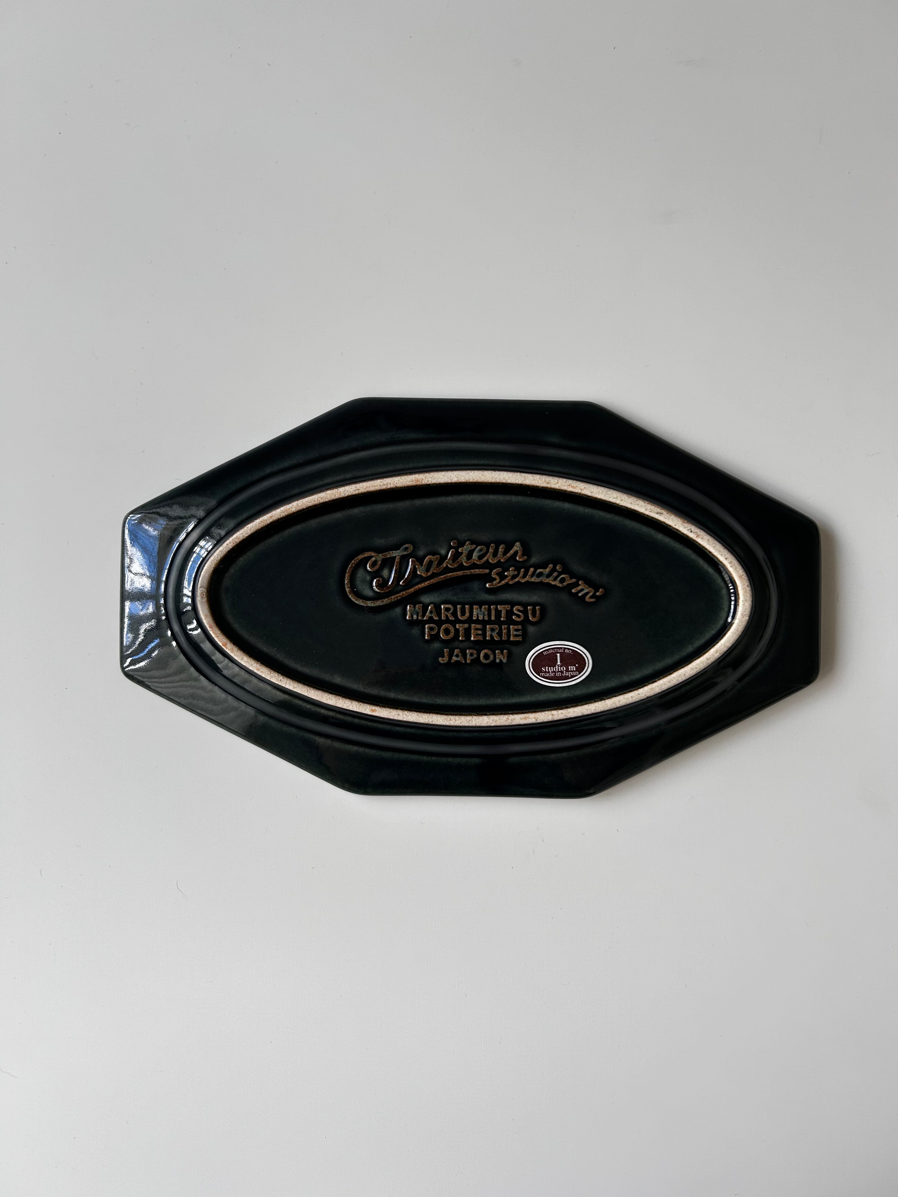 Black decorative plate with a logo on a gray background
