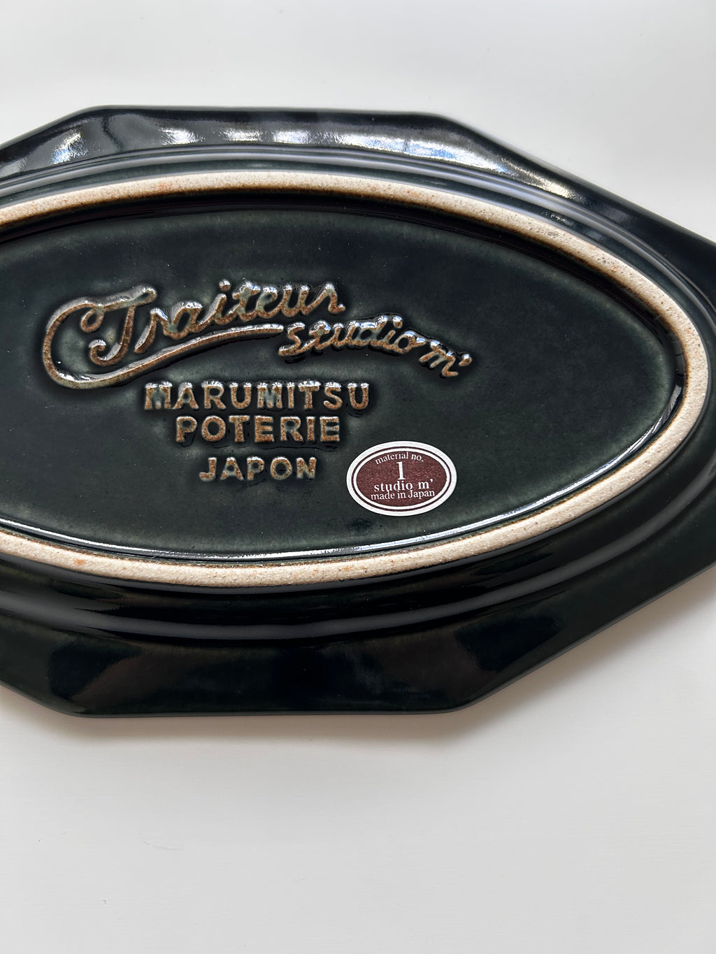 Black ceramic dish with 'Marumitsu Poterie Japon' branding on a white background